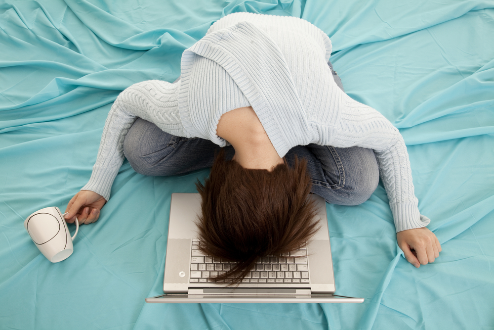 a woman showing frustration hitting her head on her laptop