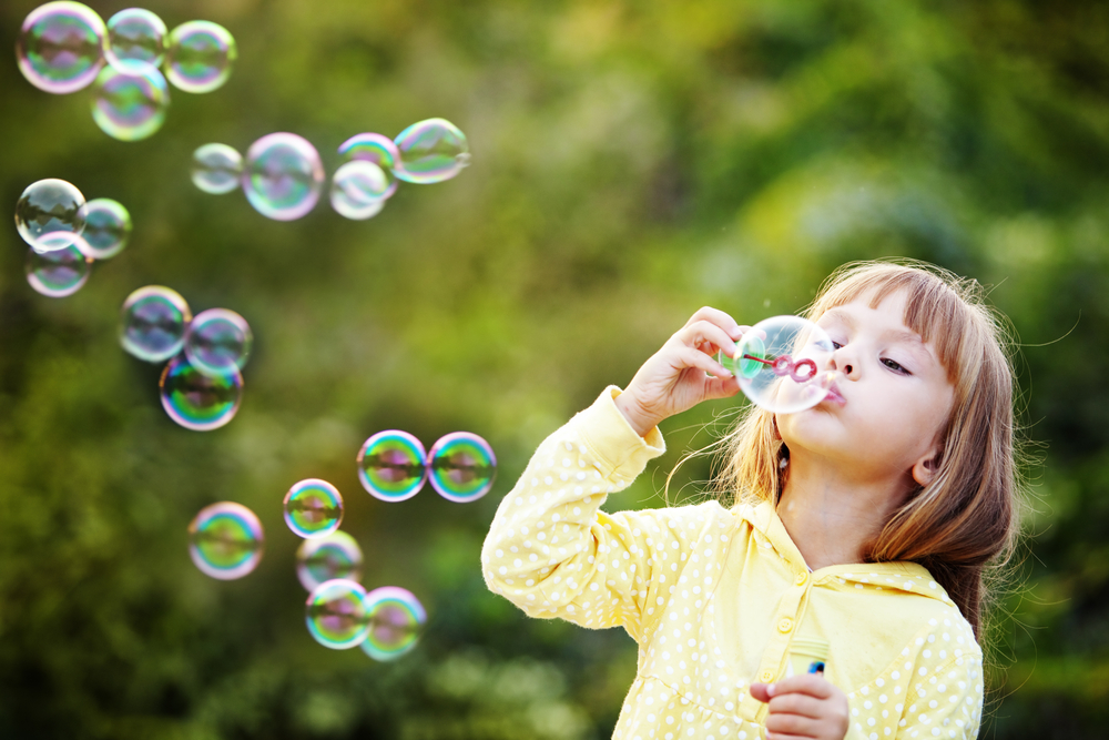 a little girl playing with a soap bubble