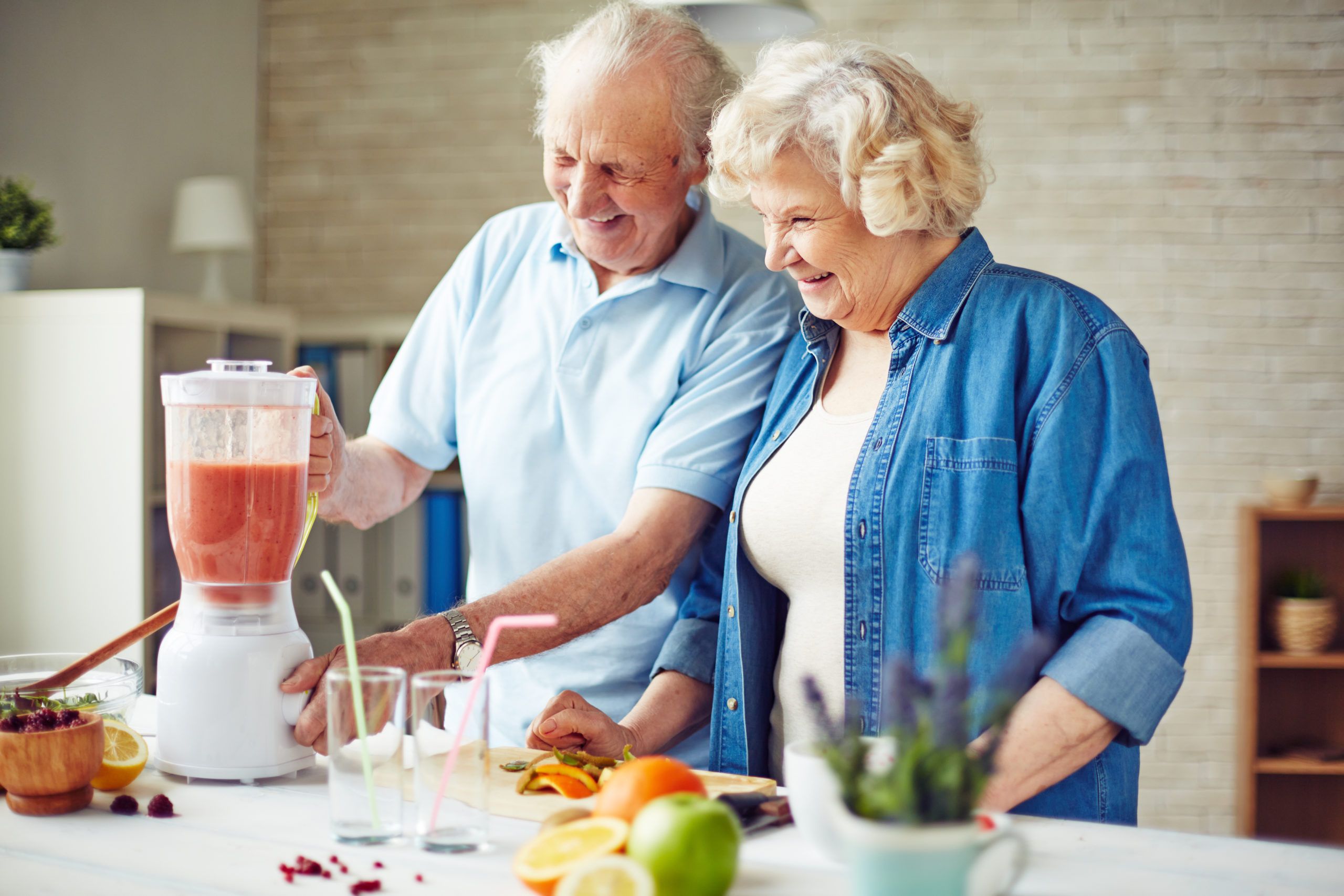 Affectionate senior couple making fruit smoothie