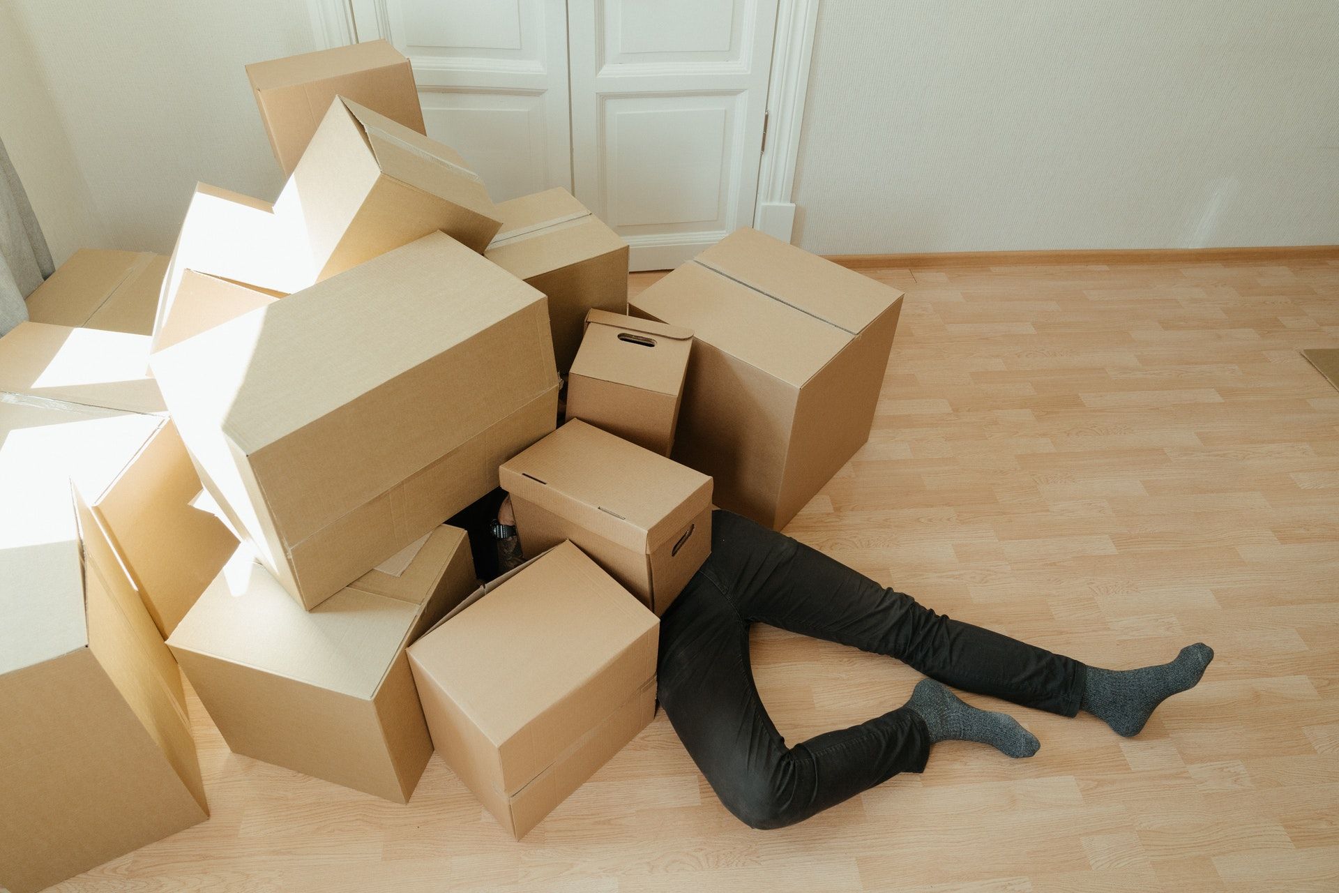 A man lying on the floor with a few cardboard boxes on him